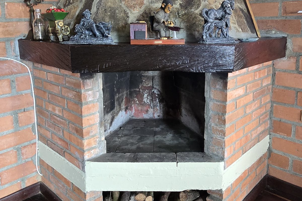 Chimenea de piedra y ladrillo con leña lista en la sala de La Amalita